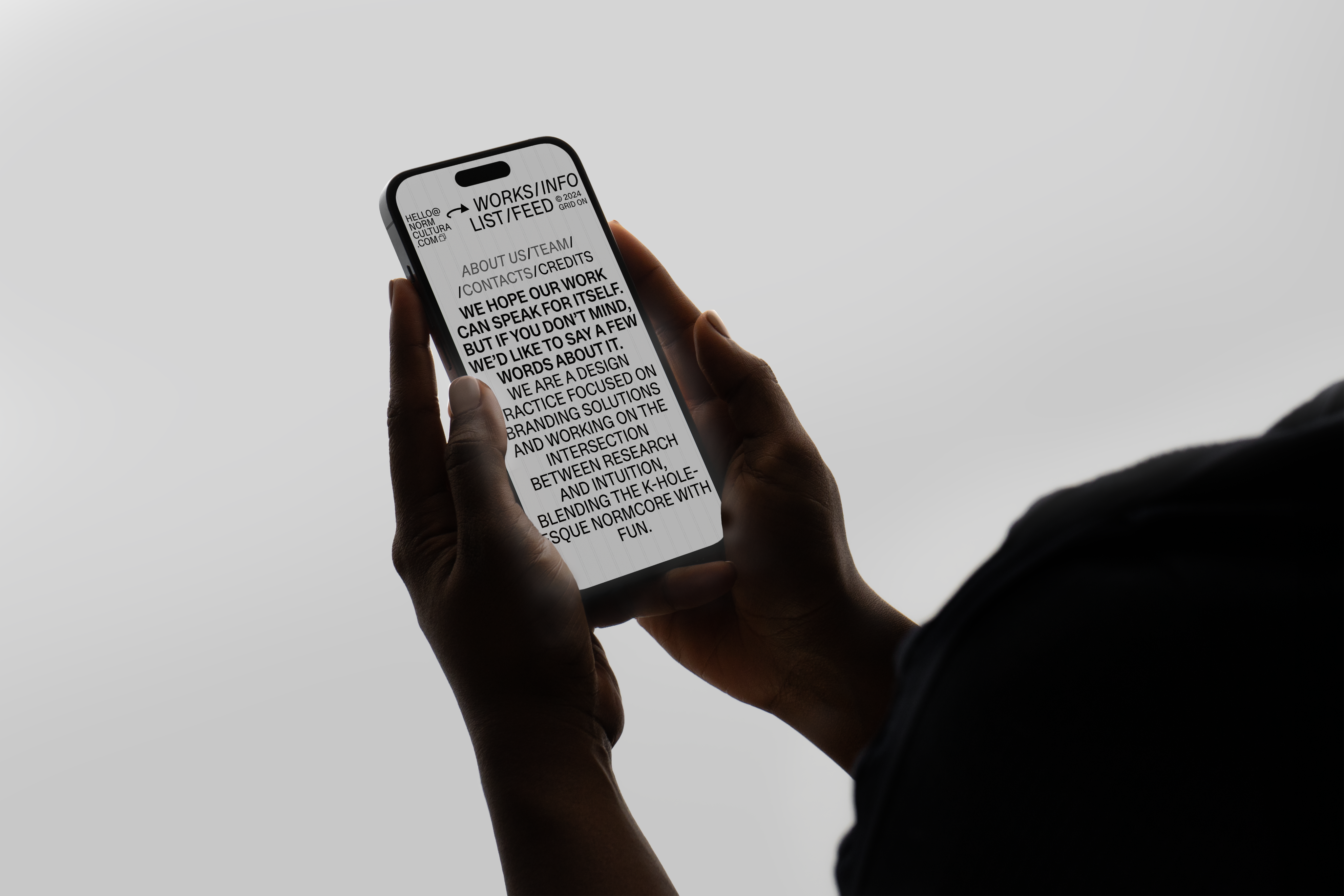 Mobile view of the Norm Cultura homepage on a phone held in both hands; ‘WORKS/INFO’ and ‘LIST/FEED’ visible.