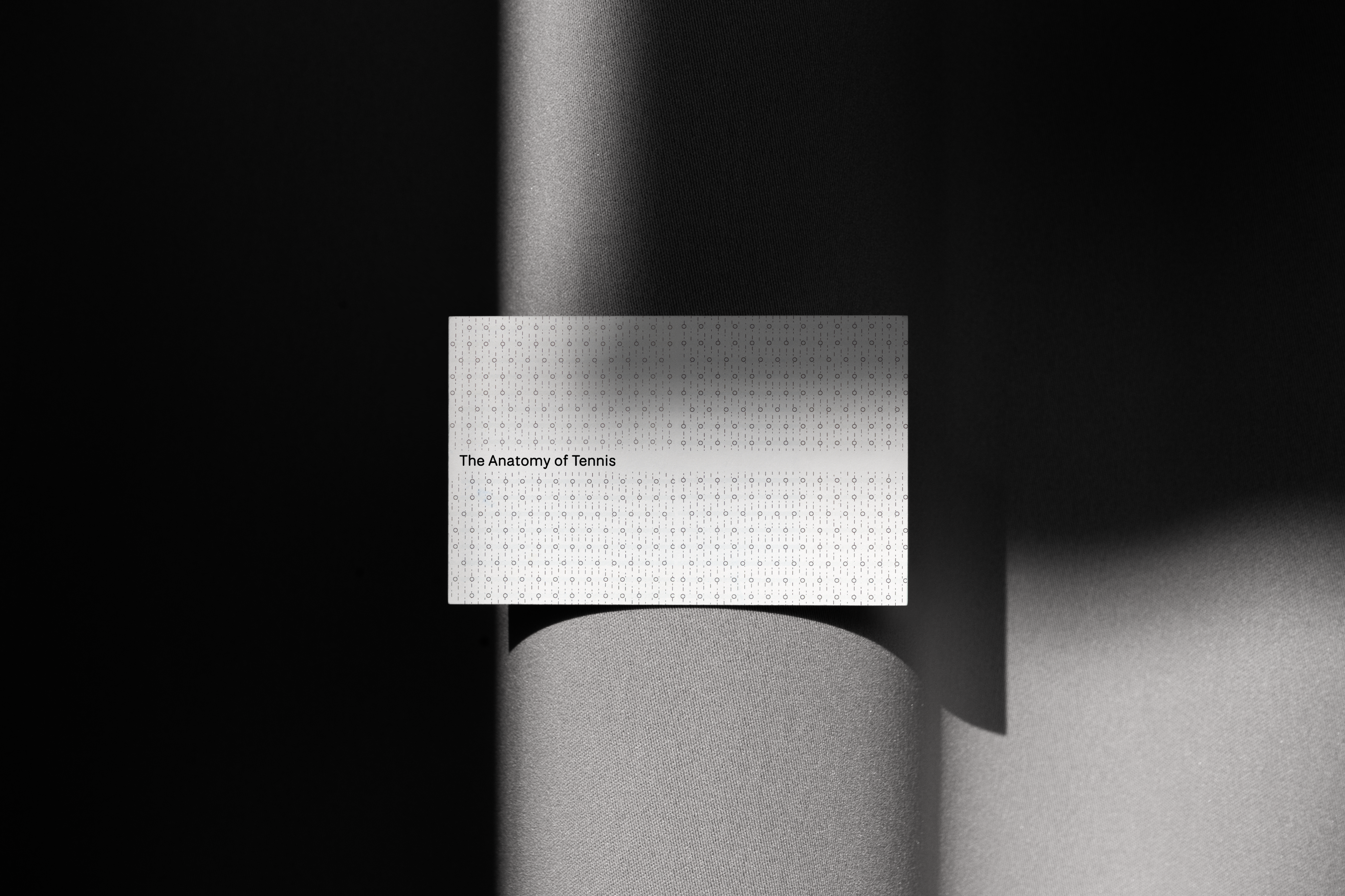 Book cover titled ‘The Anatomy of Tennis’ lit by a narrow beam across a subtle patterned background.